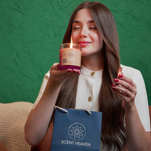 Woman closing eyes while holding Scent Heaven Gardenia candle close to face, relaxing atmosphere.